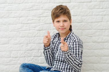 Yakışıklı, sağlıklı ve gülümseyen bir çocuk. Parmağıyla ışıklı afiş arkaplanını işaret ediyor. Fotokopi alanı var.