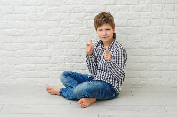 Yakışıklı, sağlıklı ve gülümseyen bir çocuk. Parmağıyla ışıklı afiş arkaplanını işaret ediyor. Fotokopi alanı var.