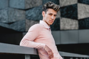 Tarz sahibi bir genç, siyah bir binanın arka planında genç. Model görünümü, şık görünüm.