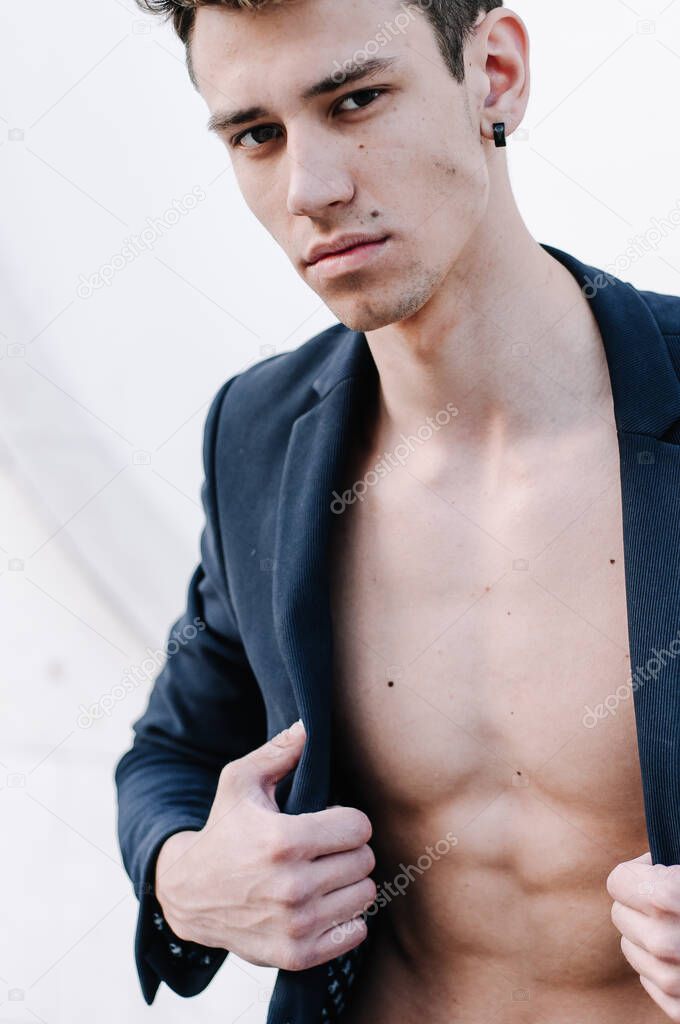 Young muscular male model in urban shots. Guy with beard and modern hairstyle in urban background.