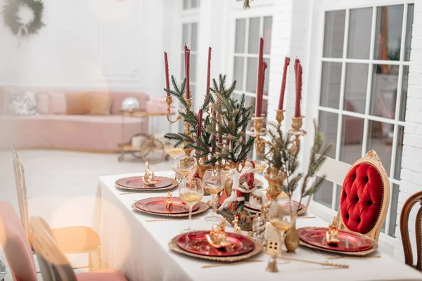 クリスマスのためのお祭りテーブル設定 赤と金の色合い 背景がぼやけている 燃えるキャンドルやクリスマスの装飾とスタイリッシュなテーブルの設定 ストック写真