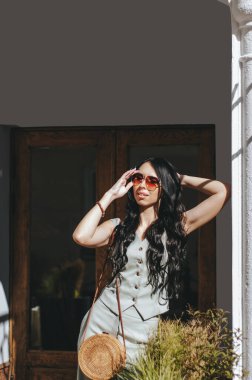 Genç mutlu, gülümseyen, uzun esmer, kıvırcık saçlı ve güneşli bir günde gülümseyen bir kızın yakın plan portresi.