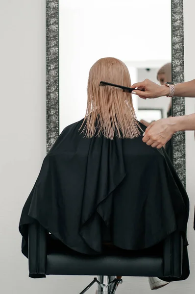 Перукарська рука з ножицями, що роблять зачіску і фарбу для волосся на фото клієнта крупним планом — стокове фото