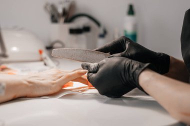 Manikür işlemi. Efendi manikür yapıyor. Tıbbi maskeli iki kadın. Manikür ustası kuaförde genç ve güzel bir kadın tırnaklıyor. Ölçülü tatmin kavramı. Boşluğu kopyala