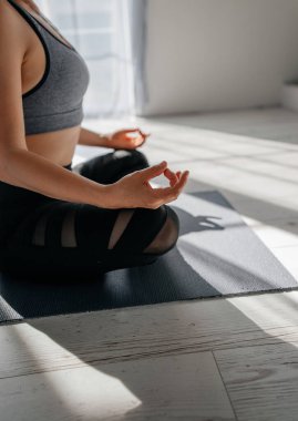 Ellerini kapat. Kız içeride yoga pratiği yapıyor. Gün batımında yoga yapan bir kadın. Spor salonunda sıcak bir geçmişi var. Genç kadın içeride meditasyon yapıyor..