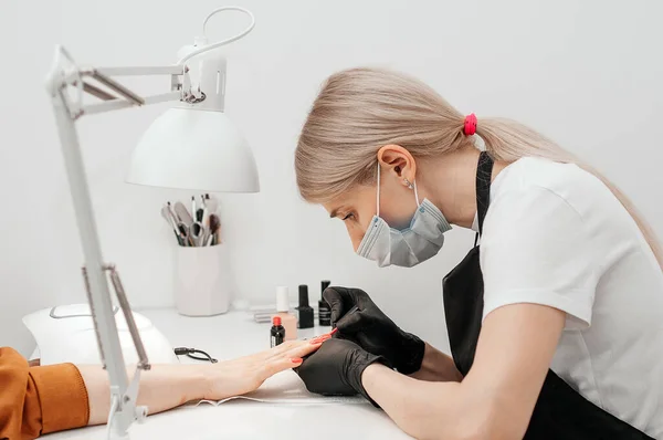 Manikür. Yakın plan. Usta müşterinin tırnaklarını cila ile kaplar..