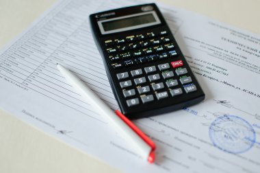 Bir sürü rakamlı hesap makinesi, kalem ve muhasebe belgesi