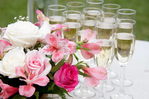 Glasögon med champagne och vackra blommor — Stockfoto