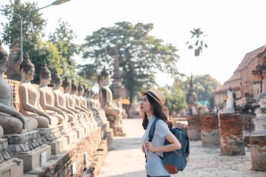 Sırt çantası taşıyan ve şapka takan Asyalı kadın turistler, Ayutthaya, Phra Nakhon 'un tarihi arkeolojik alanı Wat Yai Chaimongkol' u ziyaret ediyorlar..