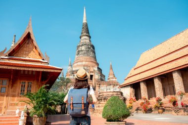 Sırt çantası taşıyan ve şapka takan Asyalı kadın turistler, Ayutthaya, Phra Nakhon 'un tarihi arkeolojik alanı Wat Yai Chaimongkol' u ziyaret ediyorlar..