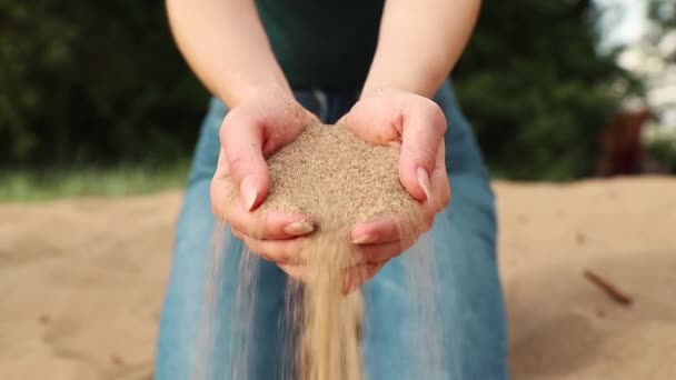 Sand fließt durch Frauenhände und Finger auf den Boden — Stockvideo