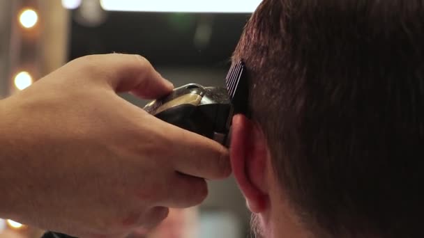 Barbiere taglia i capelli di un uomo con una macchina da barba — Video Stock