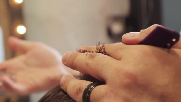 Mani di barbiere taglia i capelli di un uomo con forbici e pettine viola. Da vicino. — Video Stock