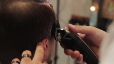 berber saç makasıyla bir adamın saçını kesiyor.