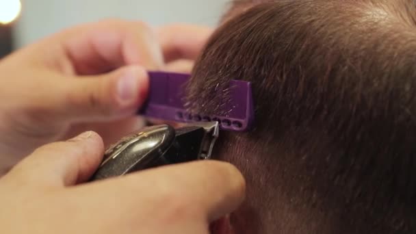 Il barbiere taglia i capelli di un uomo con una macchina da barba e un pettine viola. Da vicino. — Video Stock