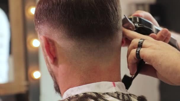 Manos de peluquero cortan el pelo de un hombre con un cortador de pelo y tijeras — Vídeos de Stock