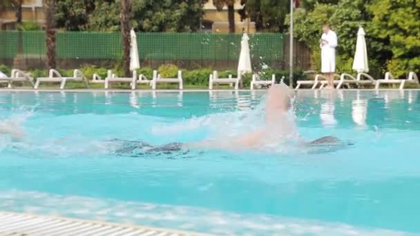 Joven barba nada en una piscina de hotel en gafas de natación — Vídeos de Stock