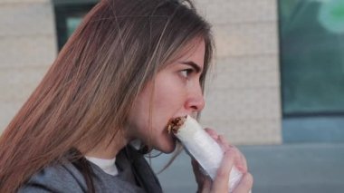 Park 'taki eğitimden sonra caddede shawarma yiyen kadın. Yaklaş, yan görüş.