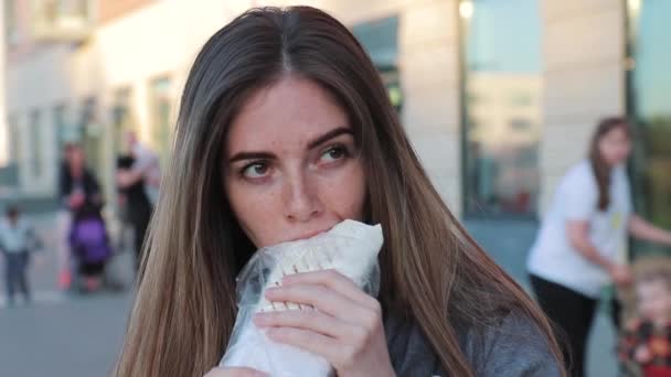 Kobieta jedzenie shawarma na ulicy po treningu w parku, zbliżenie — Wideo stockowe