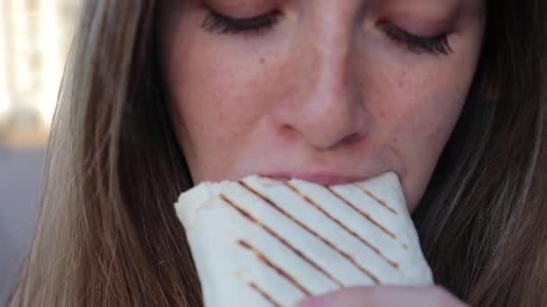 Donna mordere shawarma e guardando da qualche parte sulla strada dopo l'allenamento nel parco — Video Stock