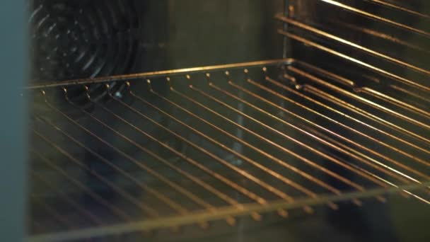 Mãos colocar uma assadeira de tortas no forno e fechar a porta — Vídeo de Stock