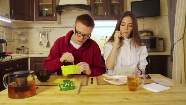 Νεαρό ζευγάρι τρώει μεσημεριανό από πλαστικά δοχεία στην κουζίνα — Αρχείο Βίντεο