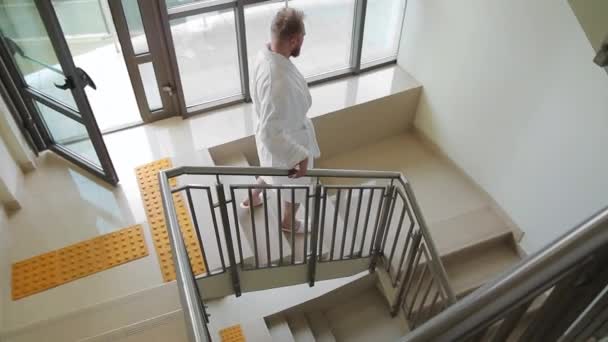 Homem de roupão branco desce as escadas do hotel — Vídeo de Stock