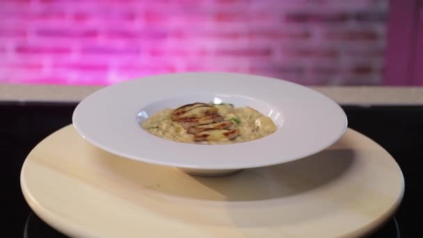 Porcini grzyb risotto na białym talerzu na fioletowej cegły tle ściany — Wideo stockowe