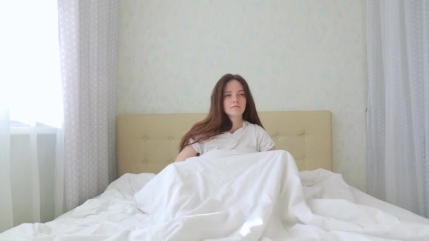 Nő ül vissza a kamerába, és nem reggeli testmozgás nyújtás karok az ágyon — Stock videók