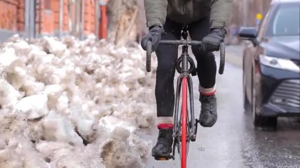 Courier rides a bike near by the car on the road in winter. Product delivery — Stock video