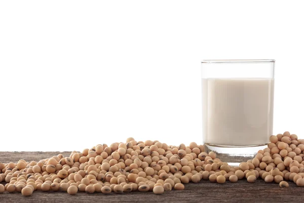 Vaso de leche de soja y frijol de soja sobre fondo de madera . Imagen De Stock