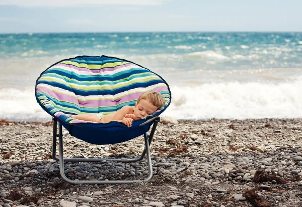 Pojke sov på stranden Stockbild