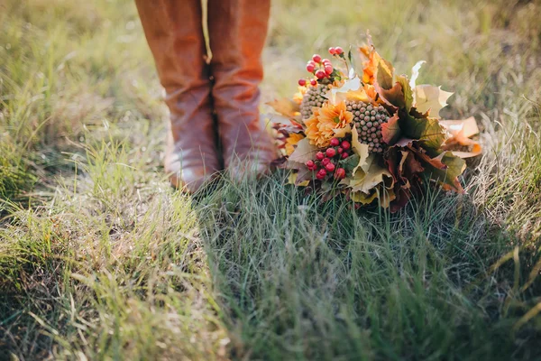 Holka v kožený boty poblíž podzimní kytice — Stock fotografie