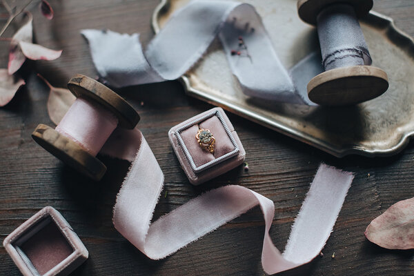 Шелковые ленты и кольцо в коробке на столе
