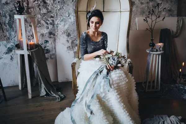 Beautiful bride in chair holding bouquet — Stock Photo, Image