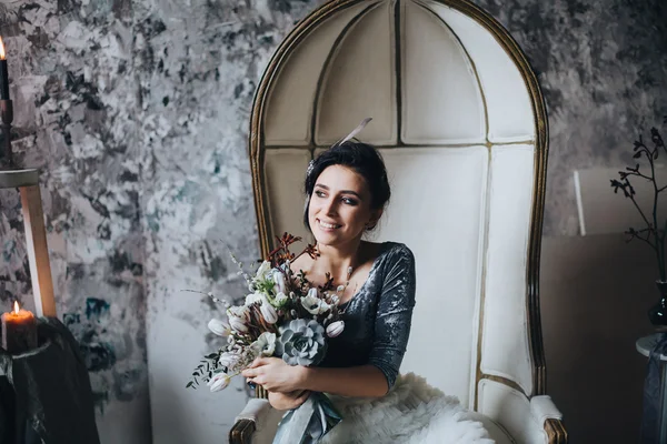 Όμορφη νύφη στην καρέκλα κρατώντας την ανθοδέσμη — Φωτογραφία Αρχείου