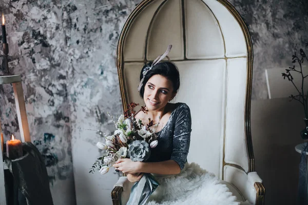 Όμορφη νύφη στην καρέκλα κρατώντας την ανθοδέσμη — Φωτογραφία Αρχείου