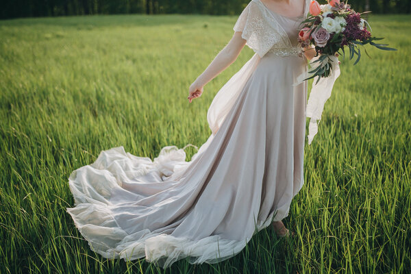 Bride in a beautiful dress with a train holding a bouquet of flowers