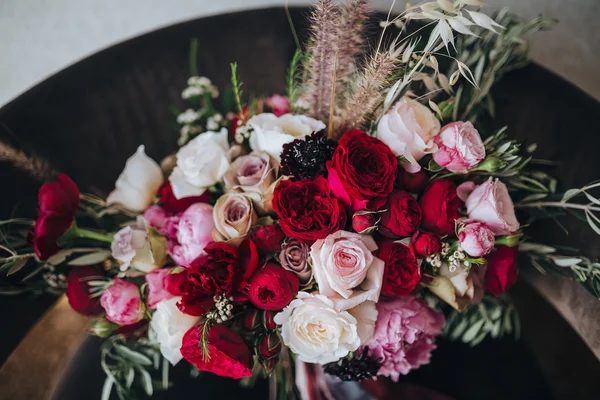 Esküvői. Boutonniere. Gabona. Grafika. Egy csokor piros virágok, rózsaszín virágok és zöld selyem szalag van a fekete szék — Stock Fotó