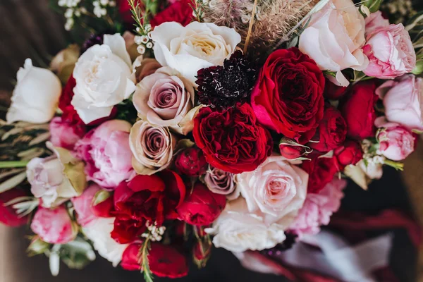 Boda. Boutonniere. Grano. Obras de arte. Un ramo de flores rojas, flores rosadas y vegetación con cintas de seda está en la silla negra —  Fotos de Stock