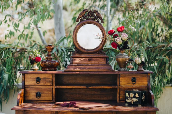Svatba. Dekor. Obilí. Umělecké dílo. Na trávníku stojí vinobraní dřevěného stolu, na stole jsou složení květin a zeleně — Stock fotografie