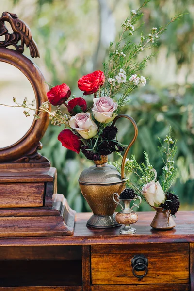 Pernikahan. Dekorasi. Biji-bijian. Karya seni. Di halaman berdiri meja kayu vintage, di atas meja adalah komposisi bunga dan hijau — Stok Foto