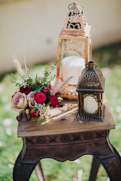 Düğün. Dekor. Tahıl. Sanat. Çimenlerin üzerinde vintage bir ahşap masa ayakları, masanın üzerine çiçek ve yeşillik bileşimi bulunmaktadır
