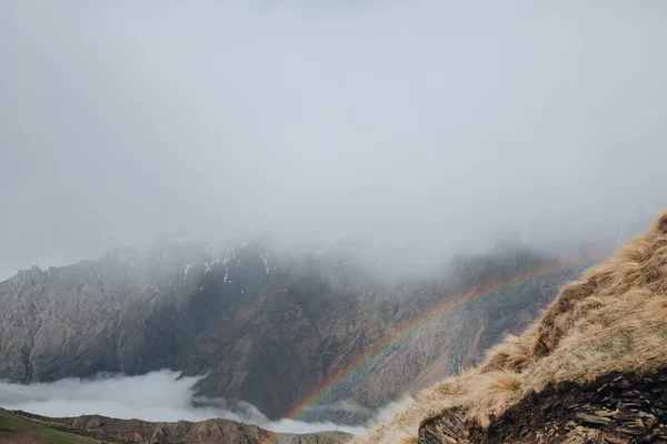 Rainbow in the mountains, peaks in the clouds — Stock Photo, Image