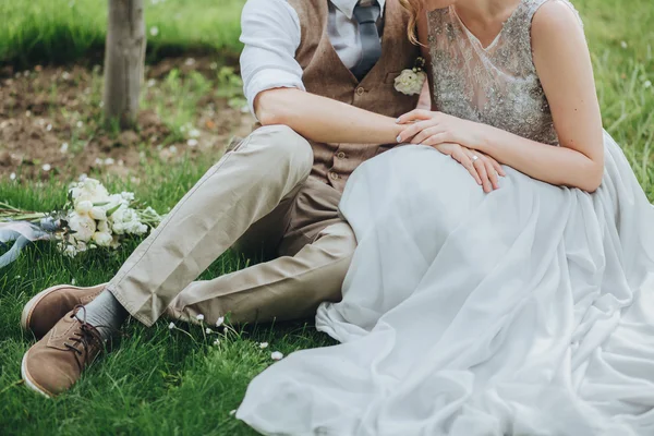 Casamento. A noiva e o noivo sentados na grama — Fotografia de Stock