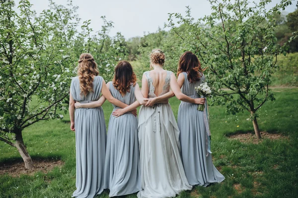 La novia de pie y damas de honor en el jardín — Foto de Stock