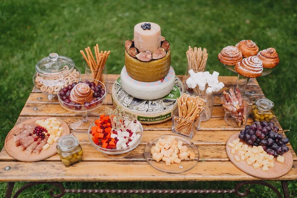 Bar à fromage sur une table en bois sur un fond d'herbe verte — Photo