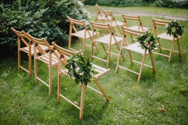 Ξύλινες καρέκλες με δάφνινο στεφάνι για ένα πράσινο γκαζόν — Φωτογραφία Αρχείου