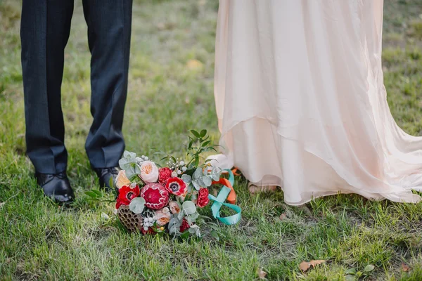 Bouquet de mariée style boho sur l'herbe verte sur un fond de la mariée et le marié Image En Vente