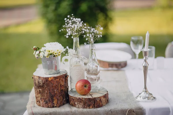 Bunga liar dalam botol kaca dan ember logam di meja pesta, meja pernikahan Stok Lukisan  